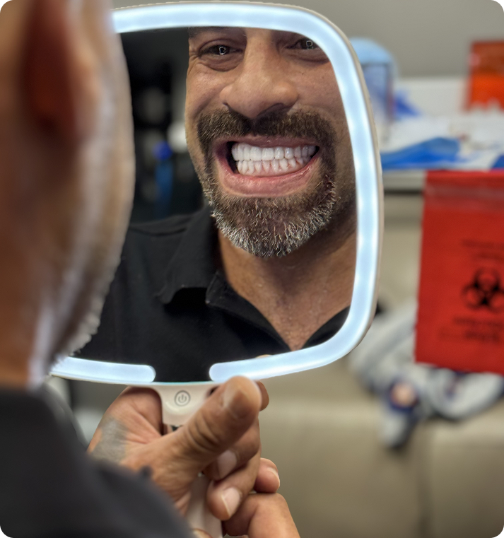Patient smiling at new teeth in a mirror